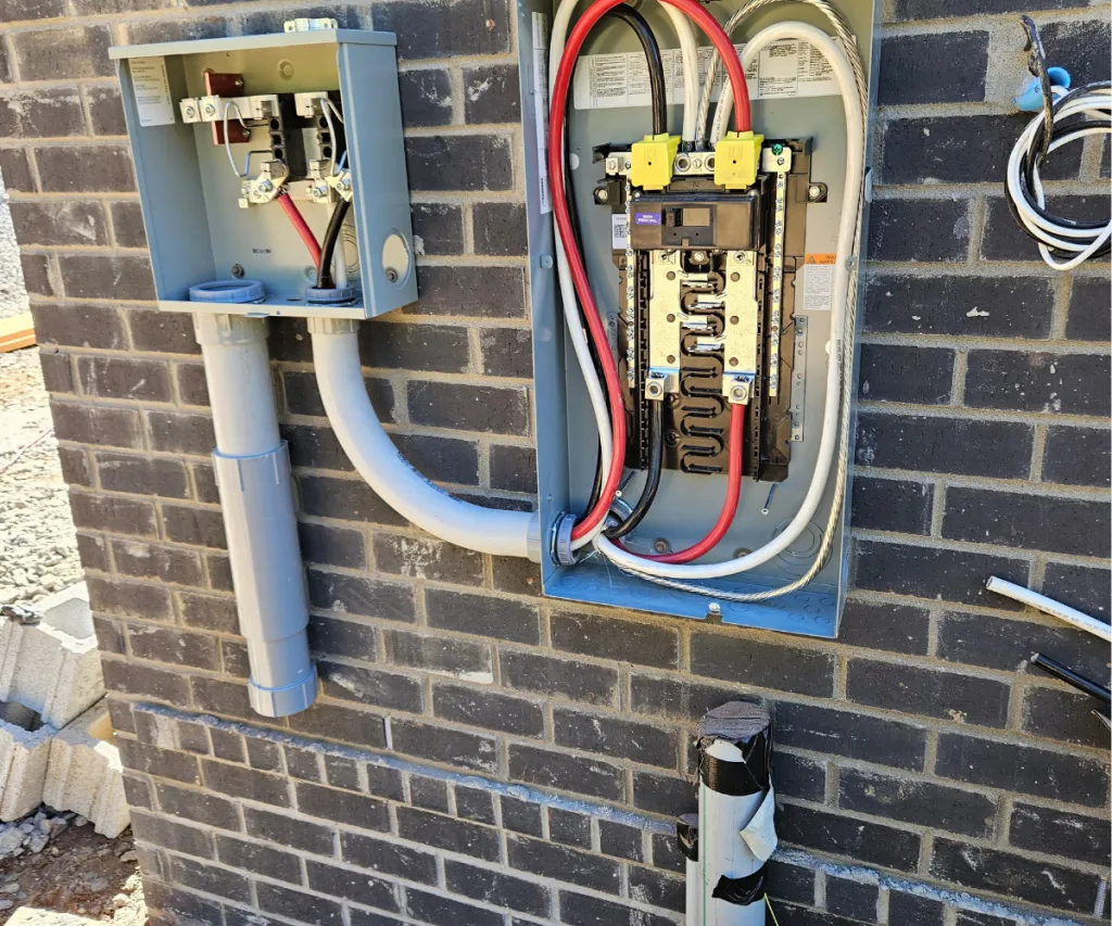 Exterior panel open on a brick wall with gray conduit runs