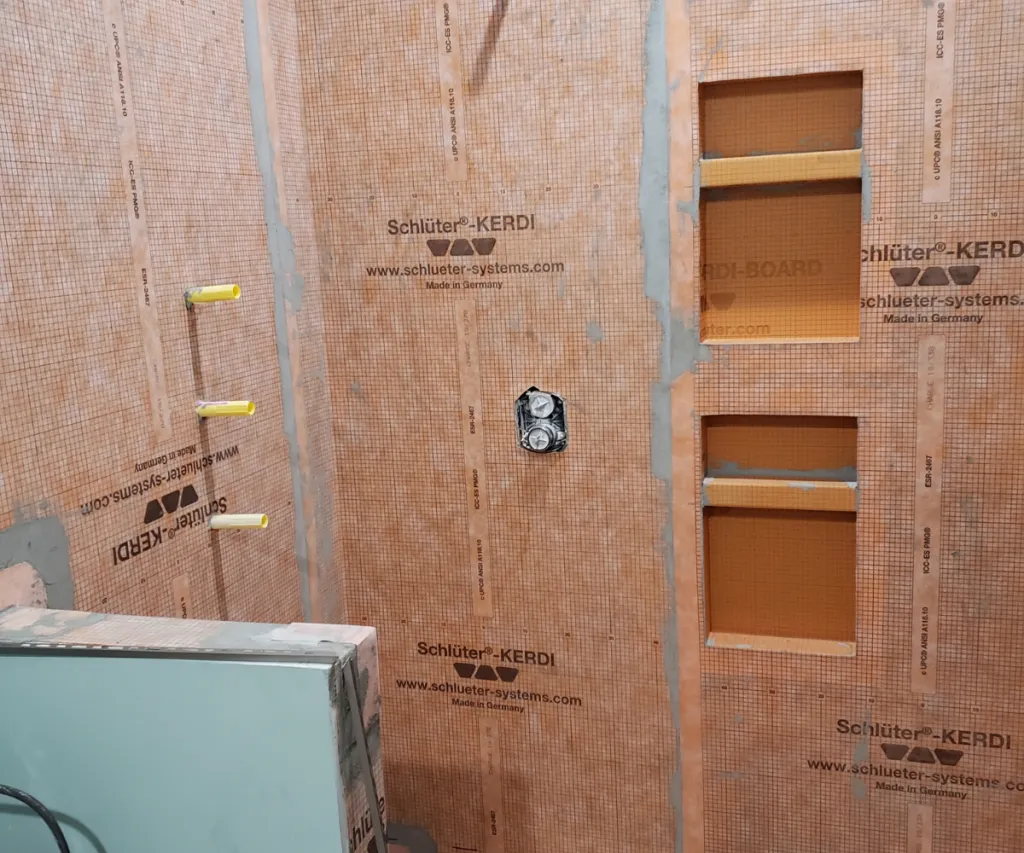 Shower wall in orange Kerdi board with two niches, the valve and supply lines roughed in