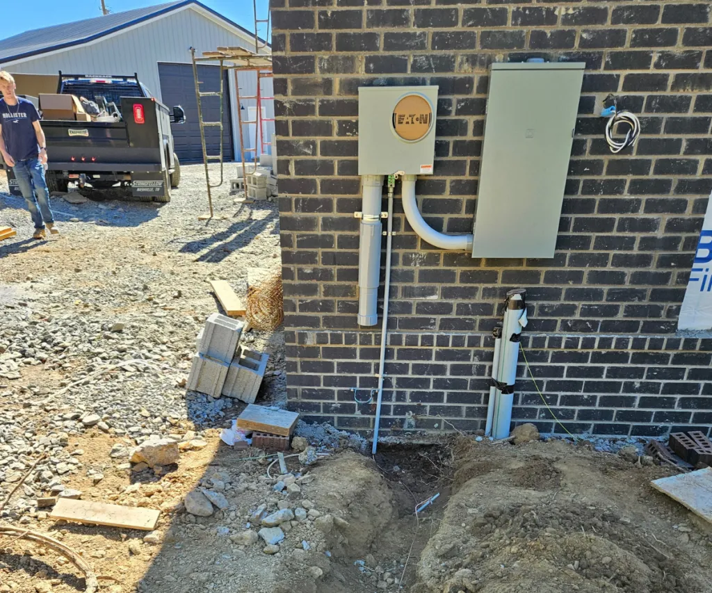 Meter base on a brick wall with a fresh trench dug below it for the new service line