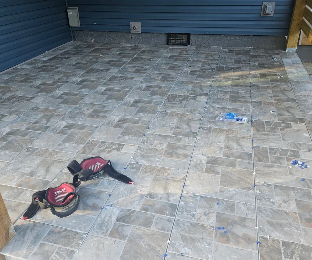 Half-finished paver patio with tools lying on it