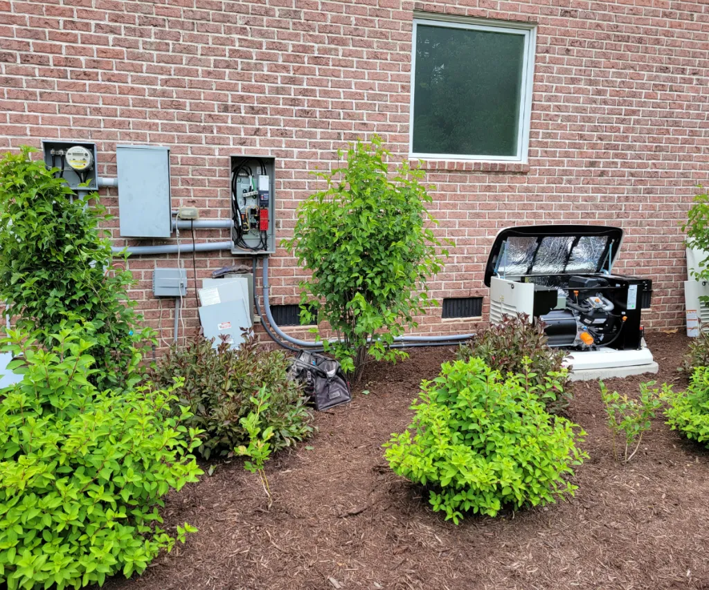 Standby generator on a pad beside a brick house, wired to the meter and transfer switch