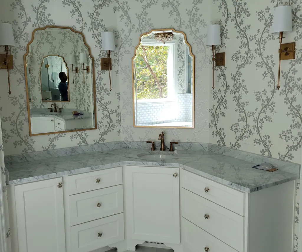 Vanity against a patterned wallpaper wall with an arched mirror